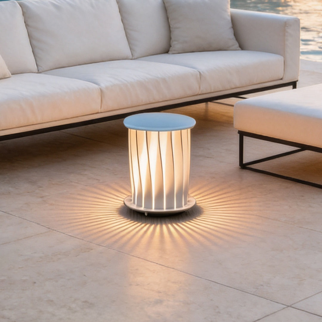 Modern outdoor lanterns casting radial light patterns on patio tiles near a white modern sofa.