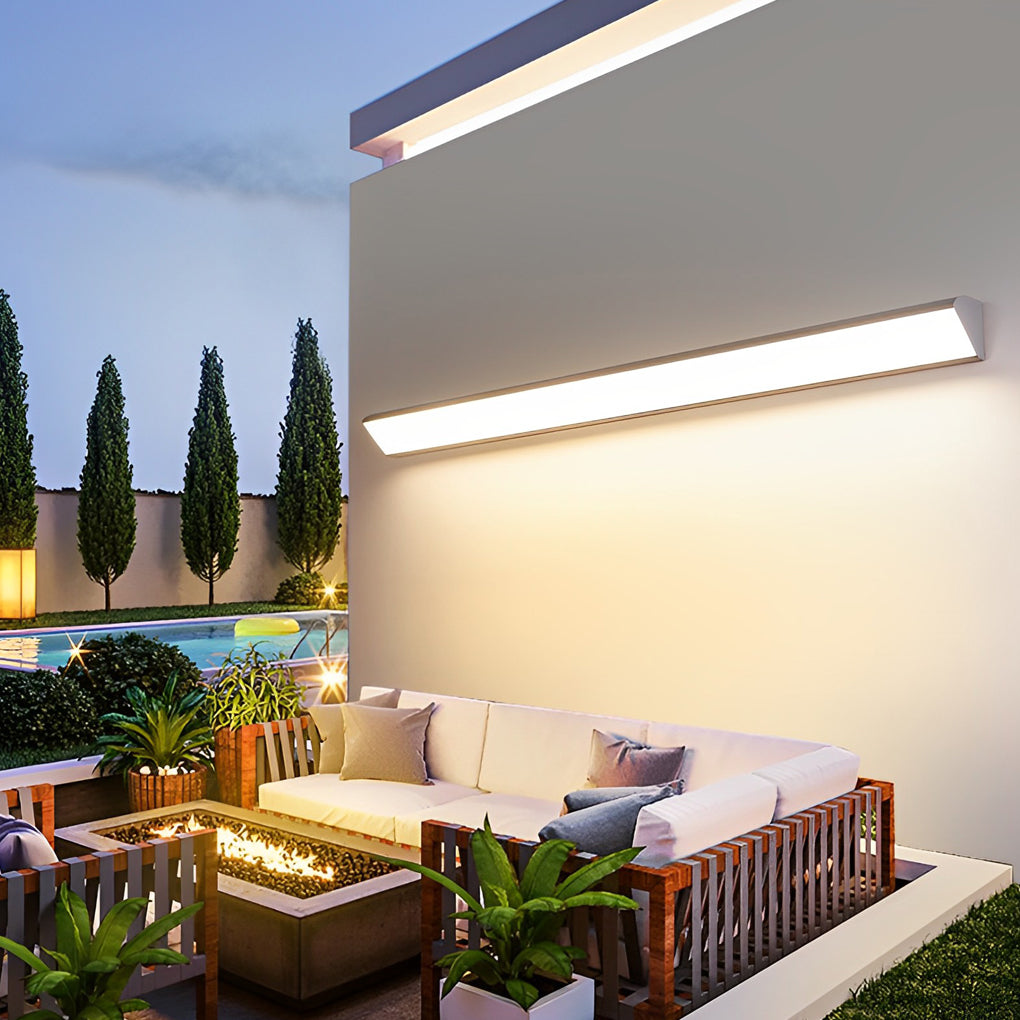Modern outdoor wall light enhancing a backyard lounge and garden seating area.