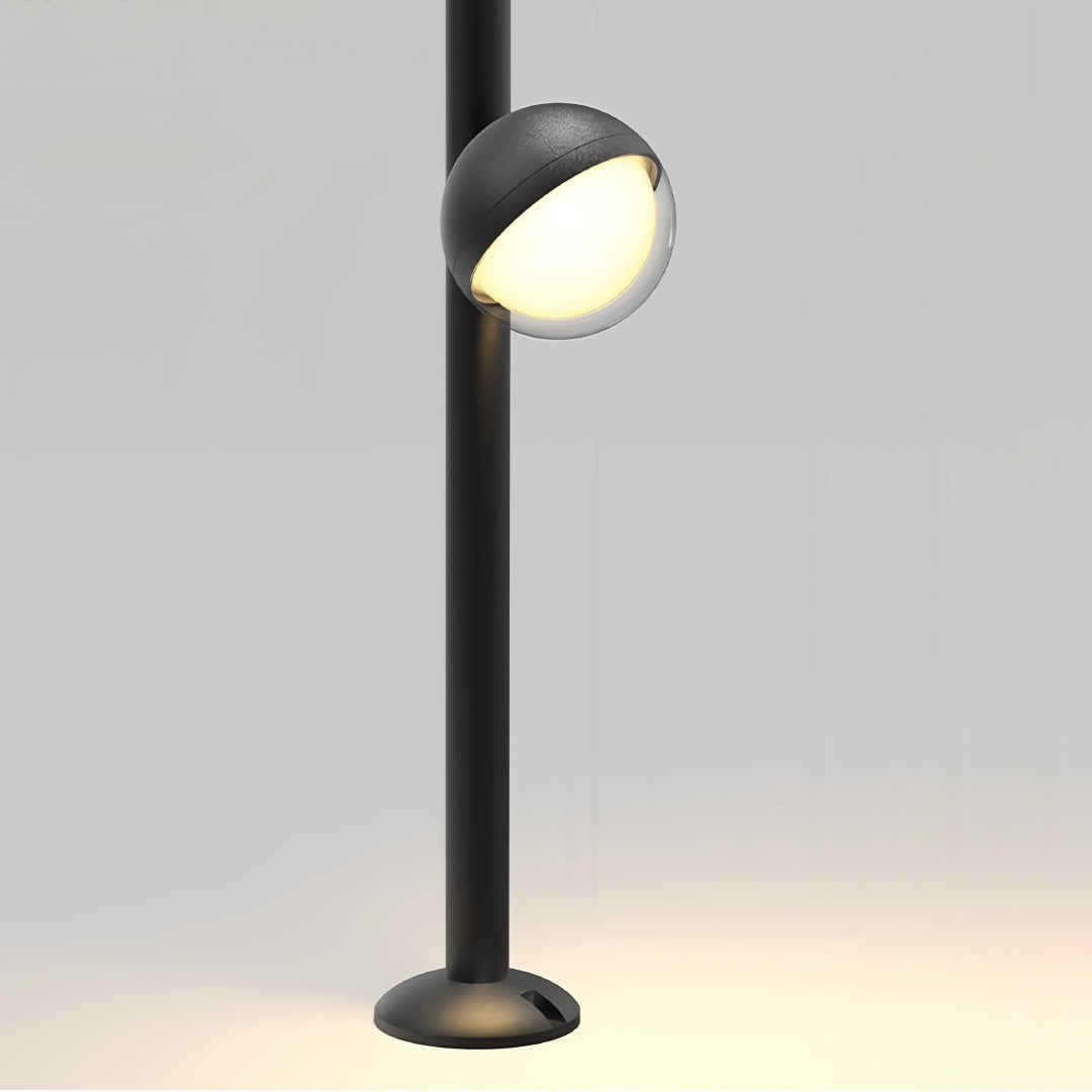 Modern pathway landscape lighting with single bollard design and round tilted head providing ambient illumination