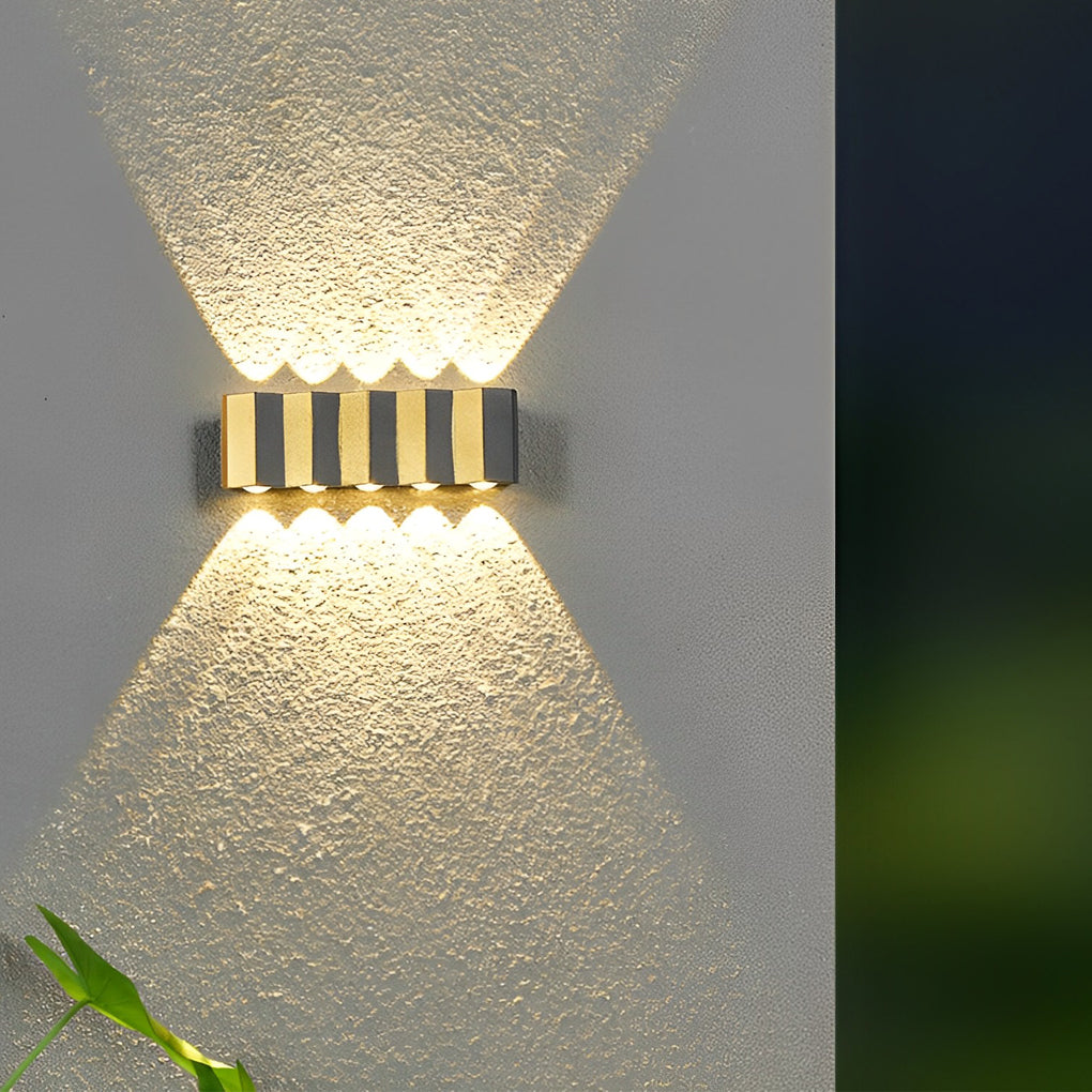 Modern up and down wall lights close-up on textured exterior wall, showing focused upward and downward light patterns.