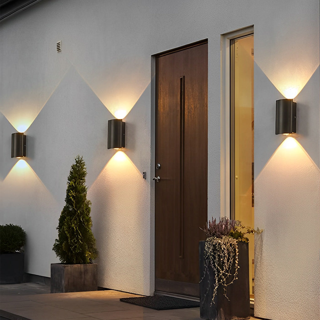 Modern up and down outdoor wall lights illuminating a cozy home entrance with potted plants and wooden door.