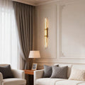 Modern vertical tube wall sconce installed beside a sofa in a living room.
