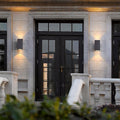 Modern wall sconce up and down light fixtures flanking a dark double door on a stone facade.