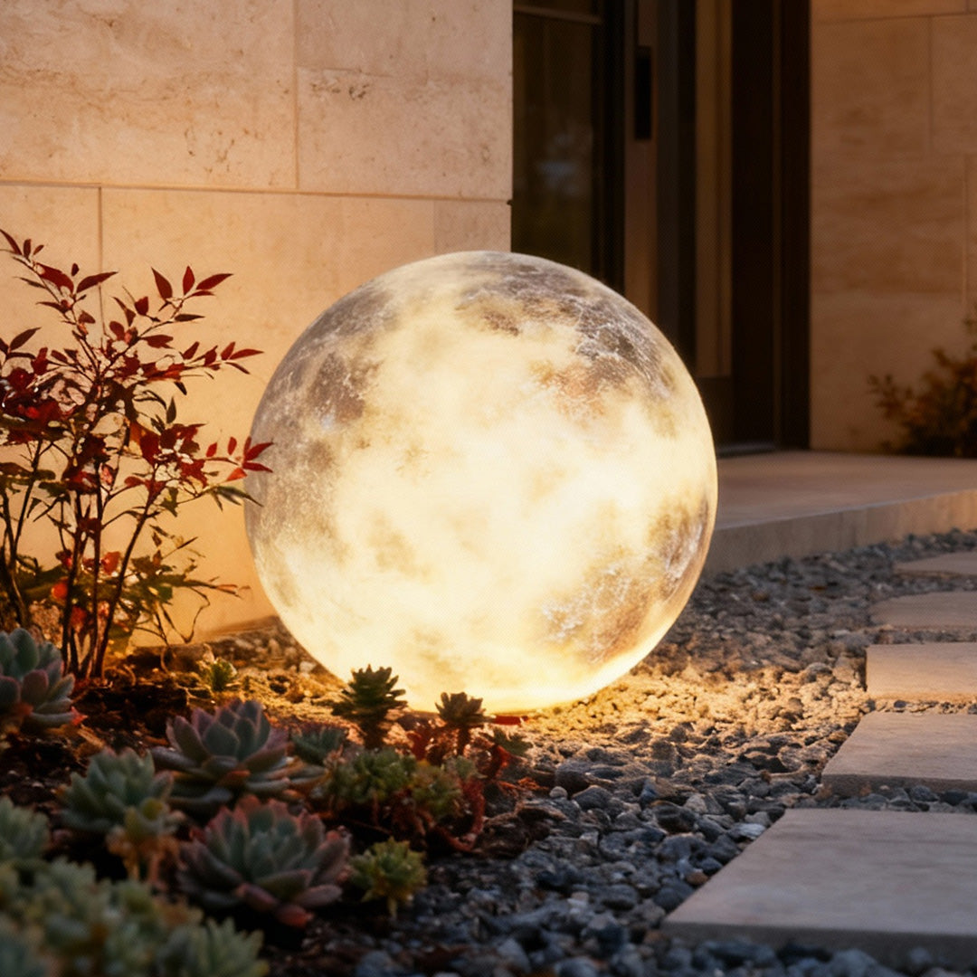 Moon light sphere resting on stone ground in a modern yard.