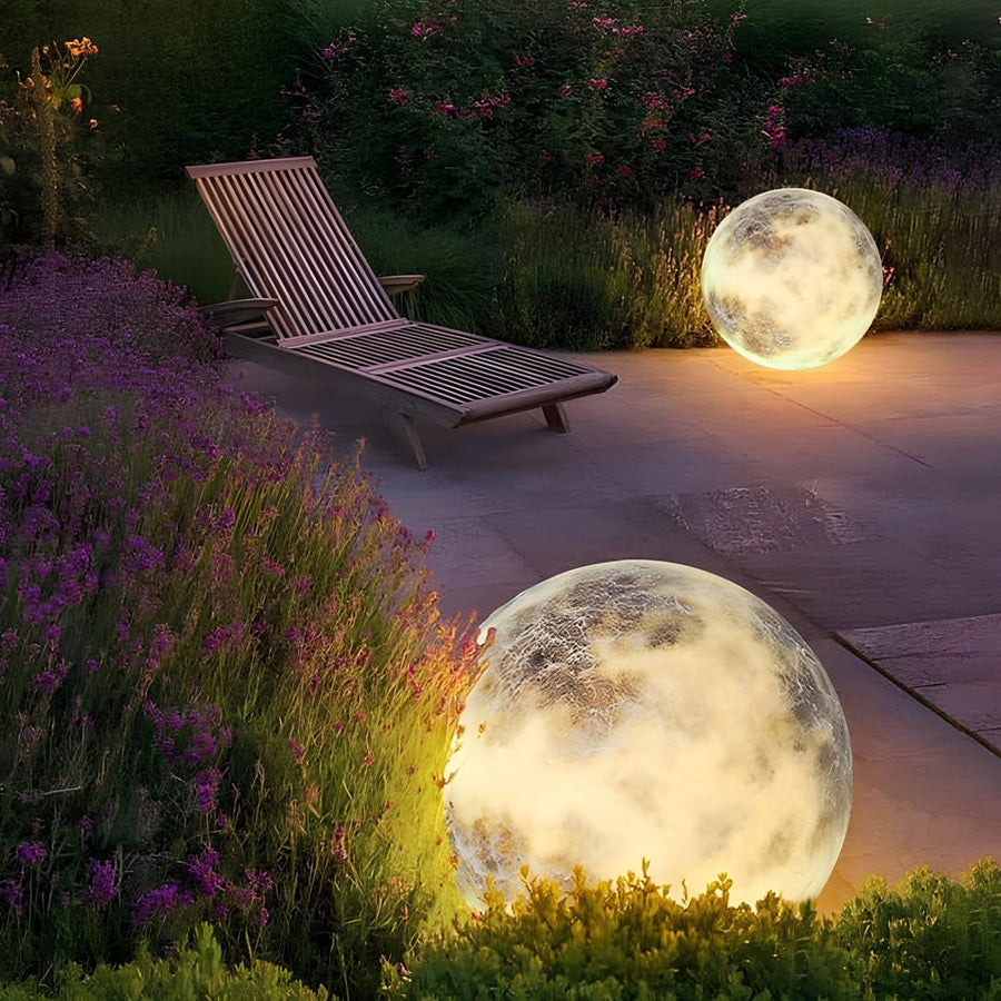 Moon light sphere beside patio lounge chairs in a garden.