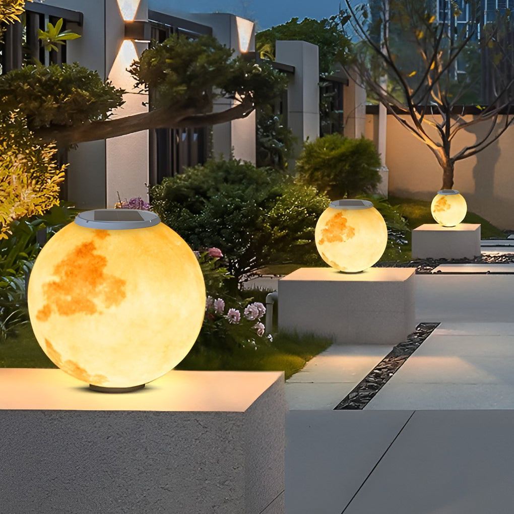 Moon pillar lights with moon pattern, illuminating modern backyard at night.