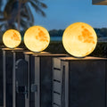 Moon pillar lights with realistic moon surface design, mounted on modern rooftop fence at dusk.