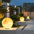 Moon-shaped stone pillar light creating ambient lighting for modern house entrance.