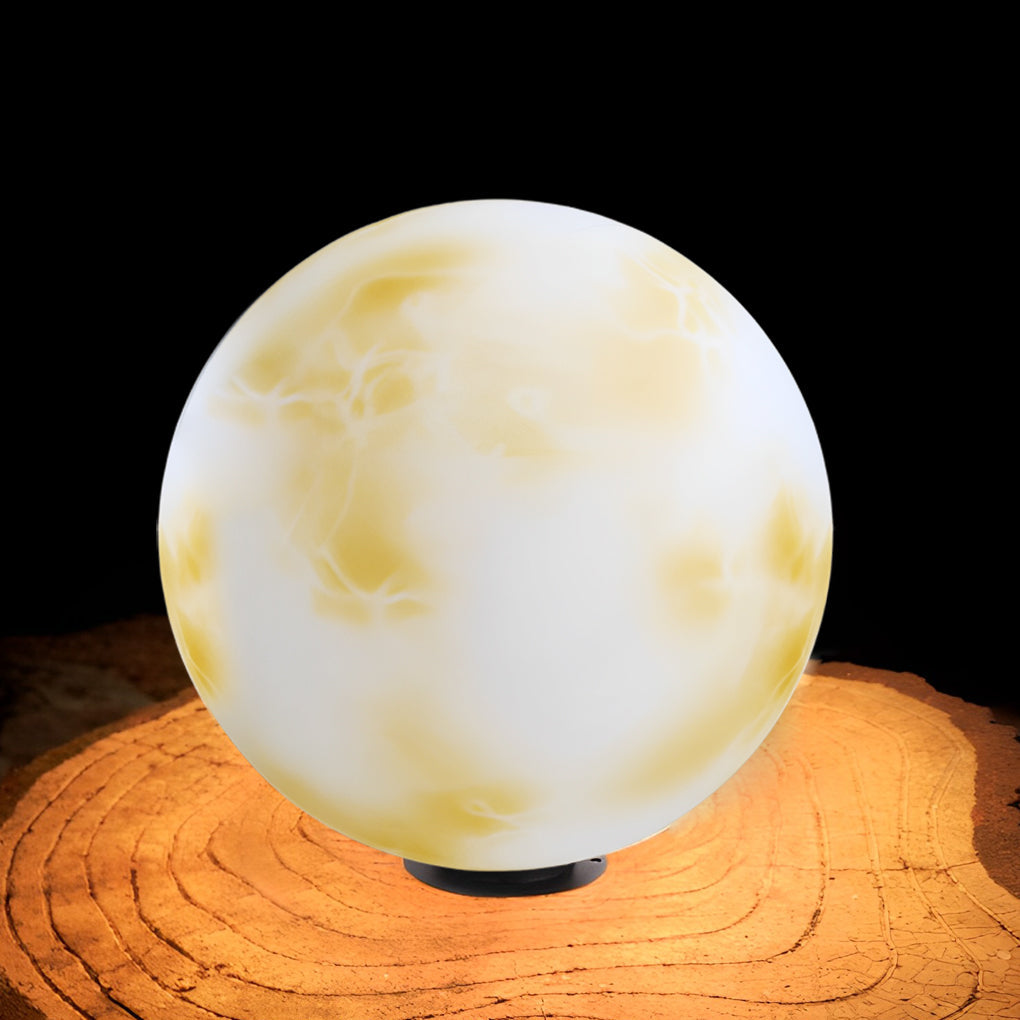Moon-shaped stone pillar light illuminating patio with modern outdoor furniture.