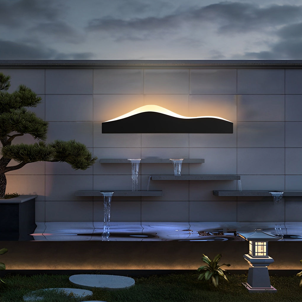 Mountain LED wall light adding ambient glow to a contemporary garden water feature.
