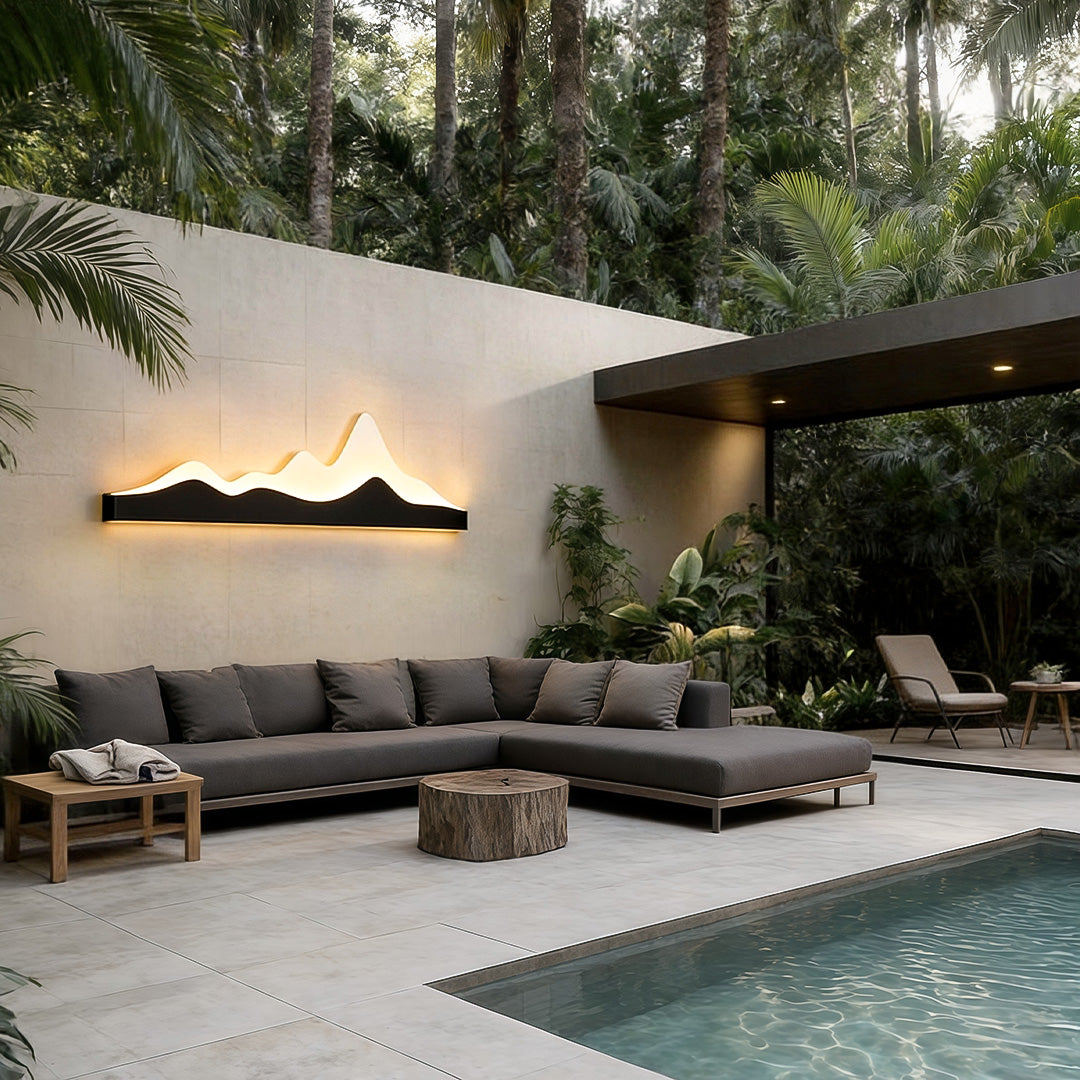 Mountain LED wall light illuminating a modern outdoor seating area beside a pool at dusk.
