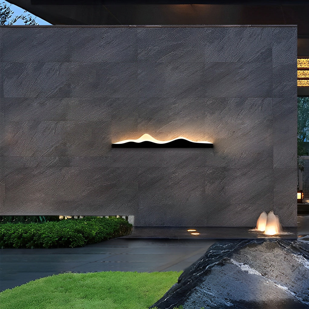 Mountain LED wall light casting a warm glow over a dark outdoor pathway.