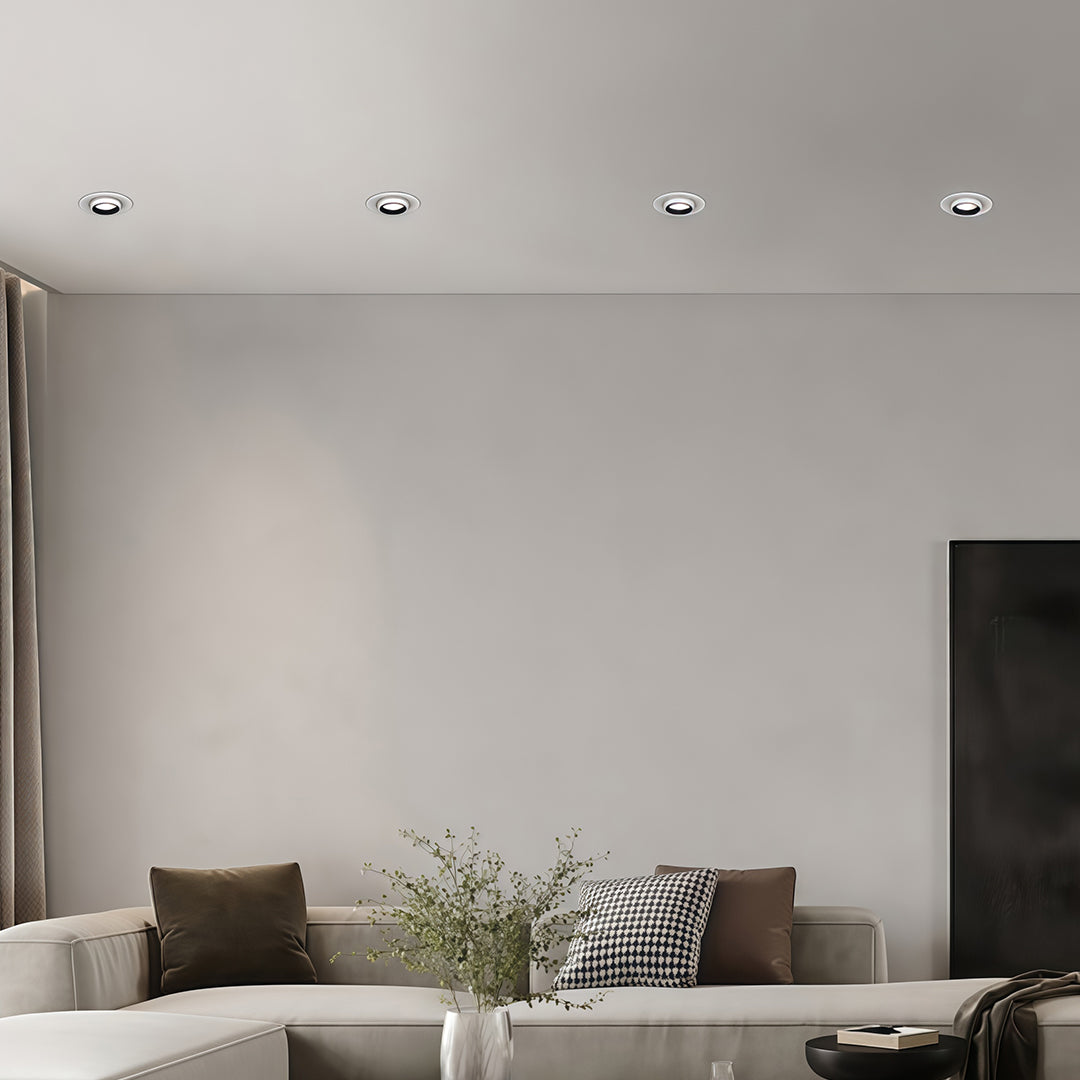 Multiple LED ceiling downlights installed over a modern living room seating area with a grey sofa.