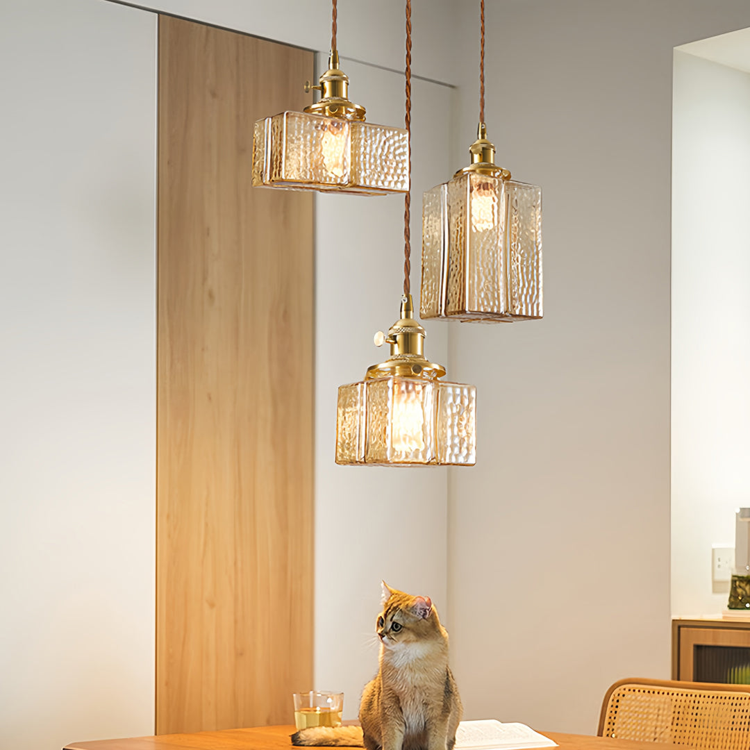 Multiple square glass pendant lights over rustic dining table creating cozy farmhouse atmosphere with natural materials.