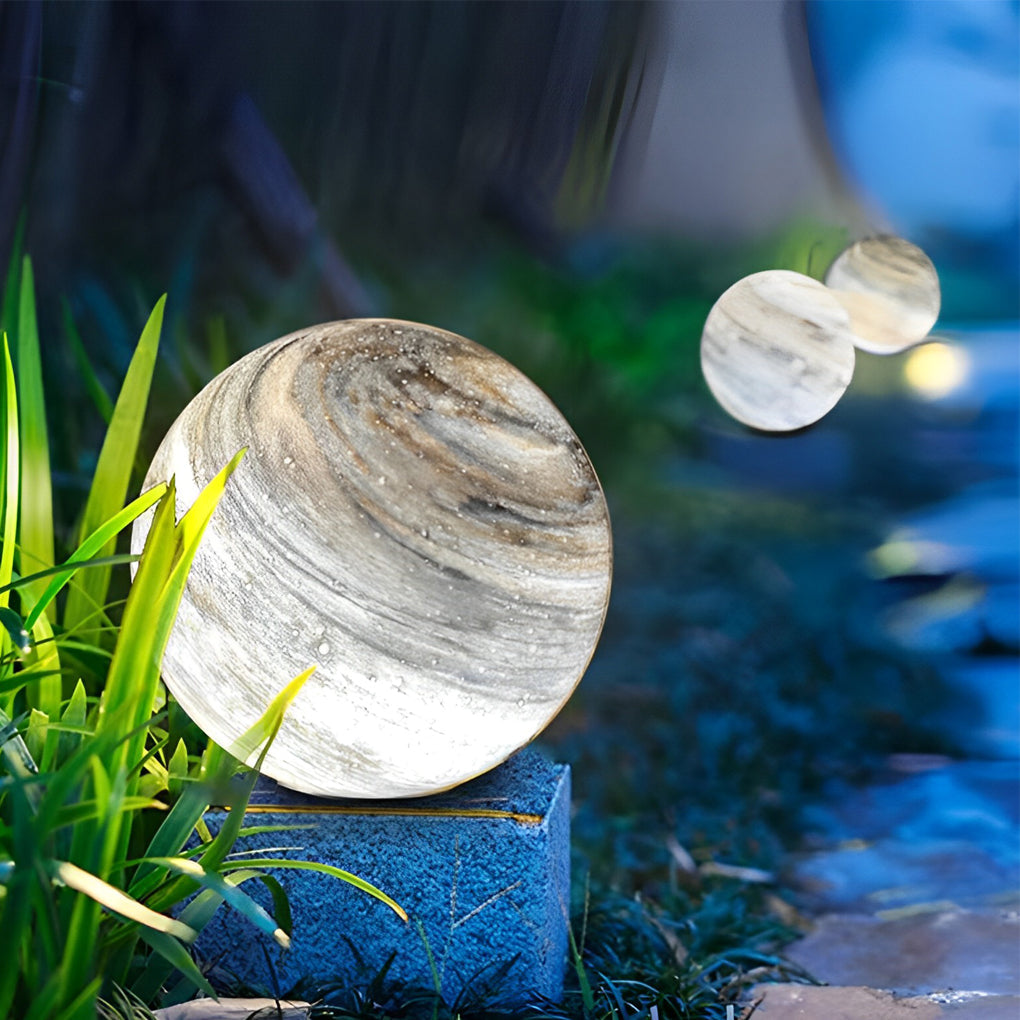Globe pillar lights with natural marble texture in garden setting.