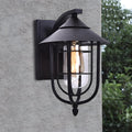 Black metal nautical wall sconce mounted on exterior wall, featuring a cage design and warm filament light.