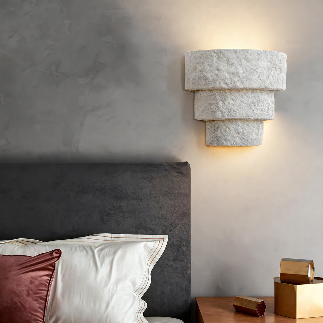 Night wall light with tapered design casting warm glow on neutral wall above wood console