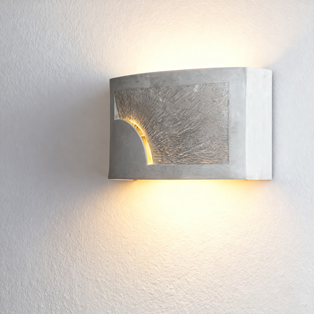 Night wall light with textured silver finish illuminating hallway beside framed artwork