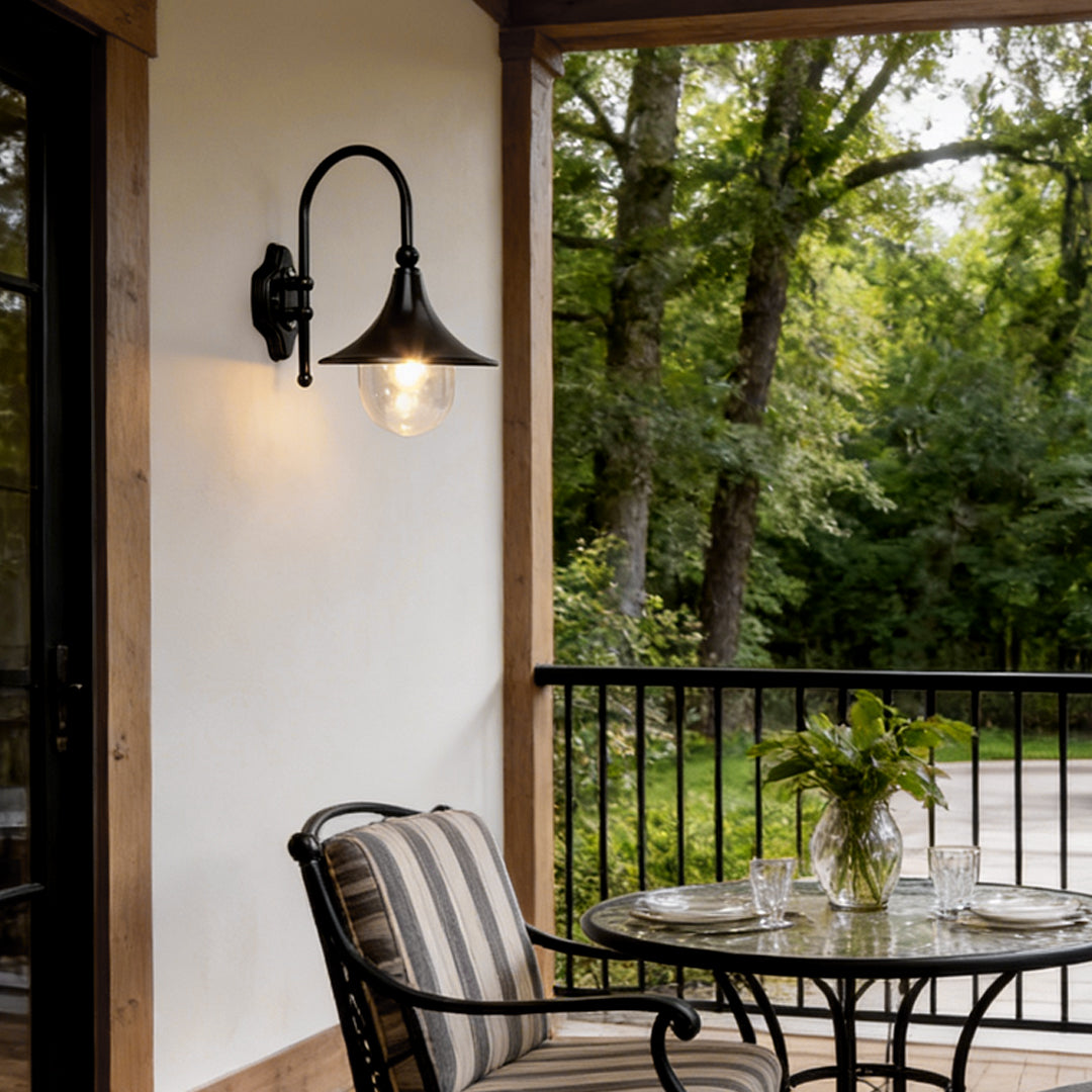 Outdoor black wall light with a classic design, illuminating a balcony with cozy seating.