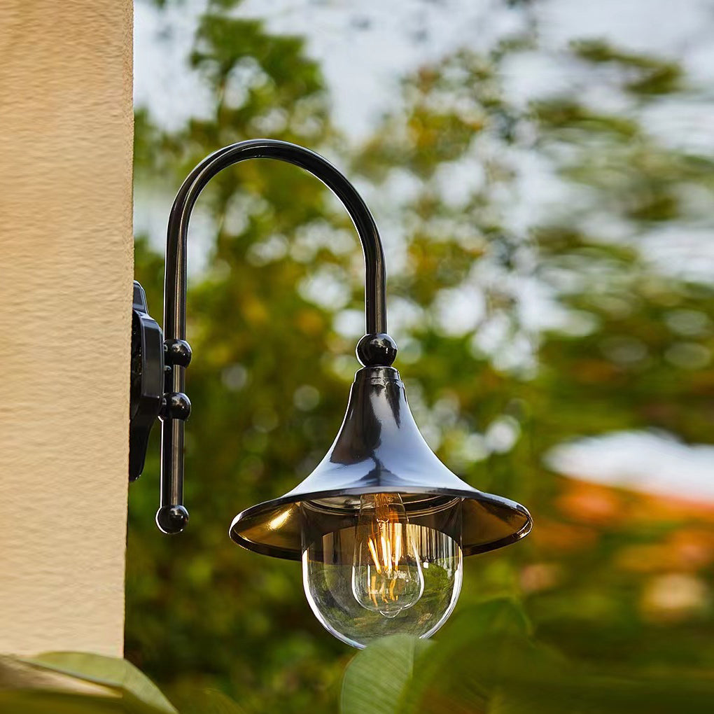 Outdoor black wall light with a classic lantern design, casting warm light on a brick wall.