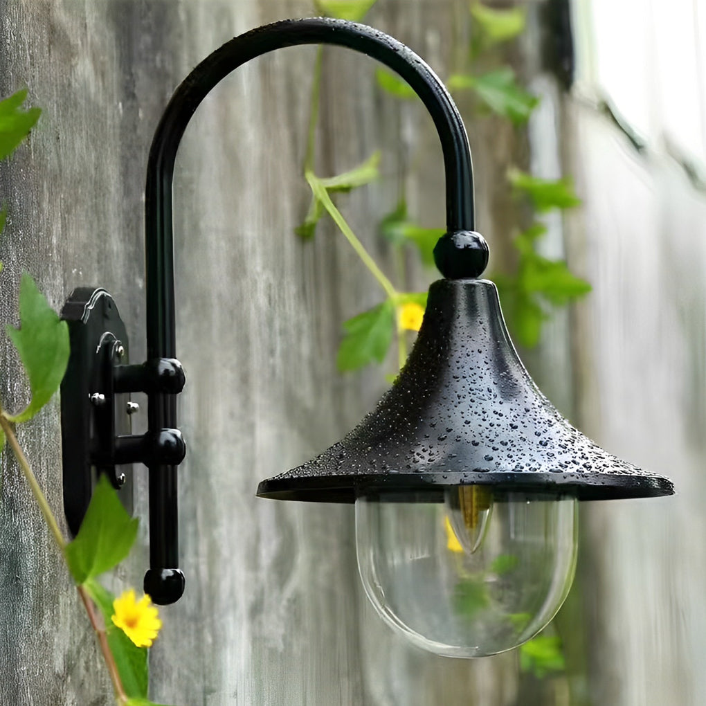 Outdoor black wall light with a curved glass shade, illuminating a garden pathway.