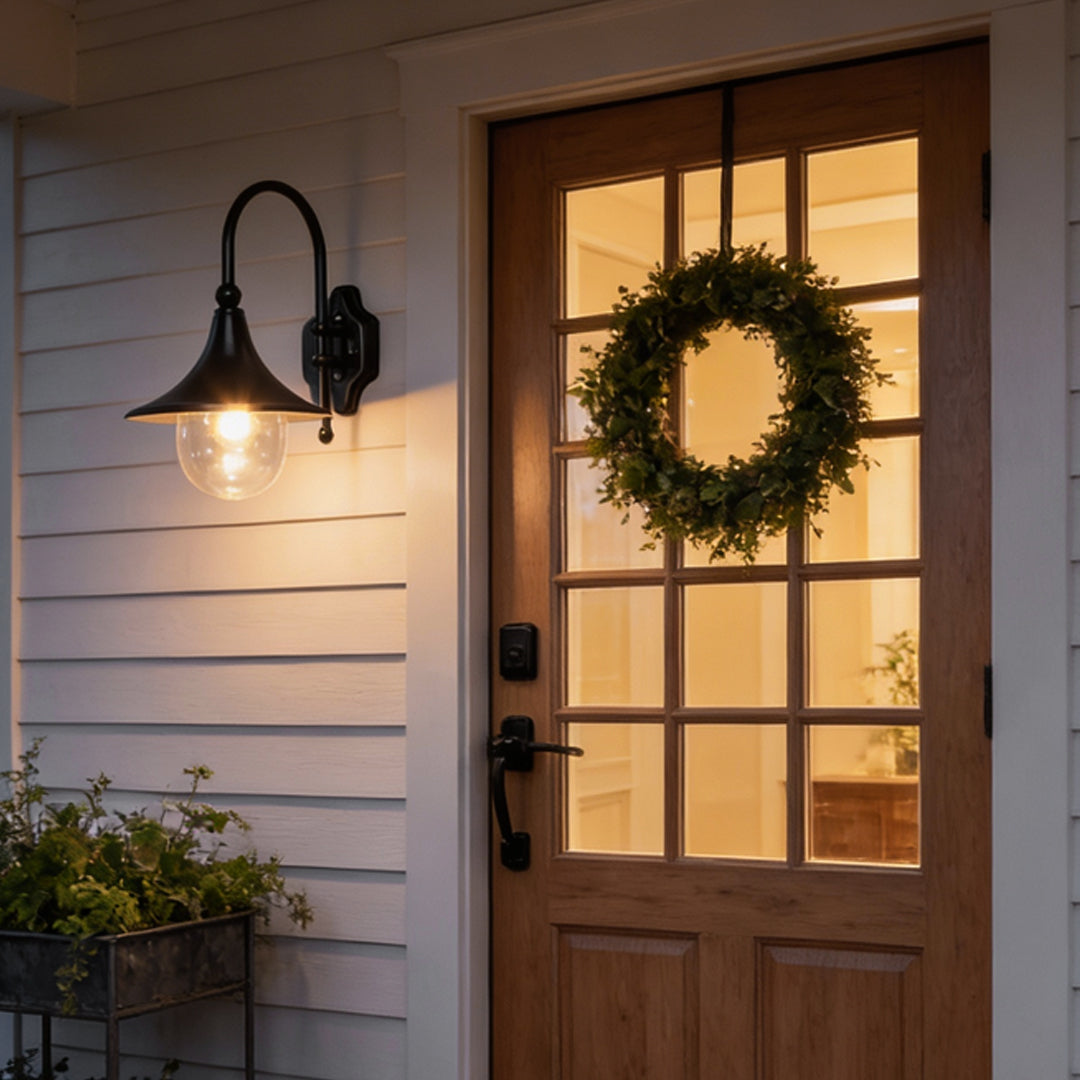 Outdoor black wall light mounted beside a wooden door, providing warm illumination for a welcoming entrance.