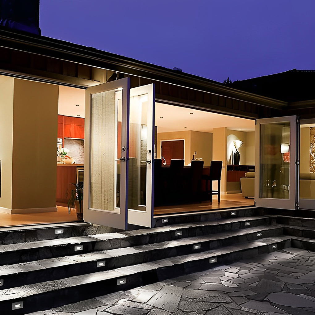 Outdoor brick light illuminating entry steps of a modern home, blending seamlessly with exterior architecture for a clean look.