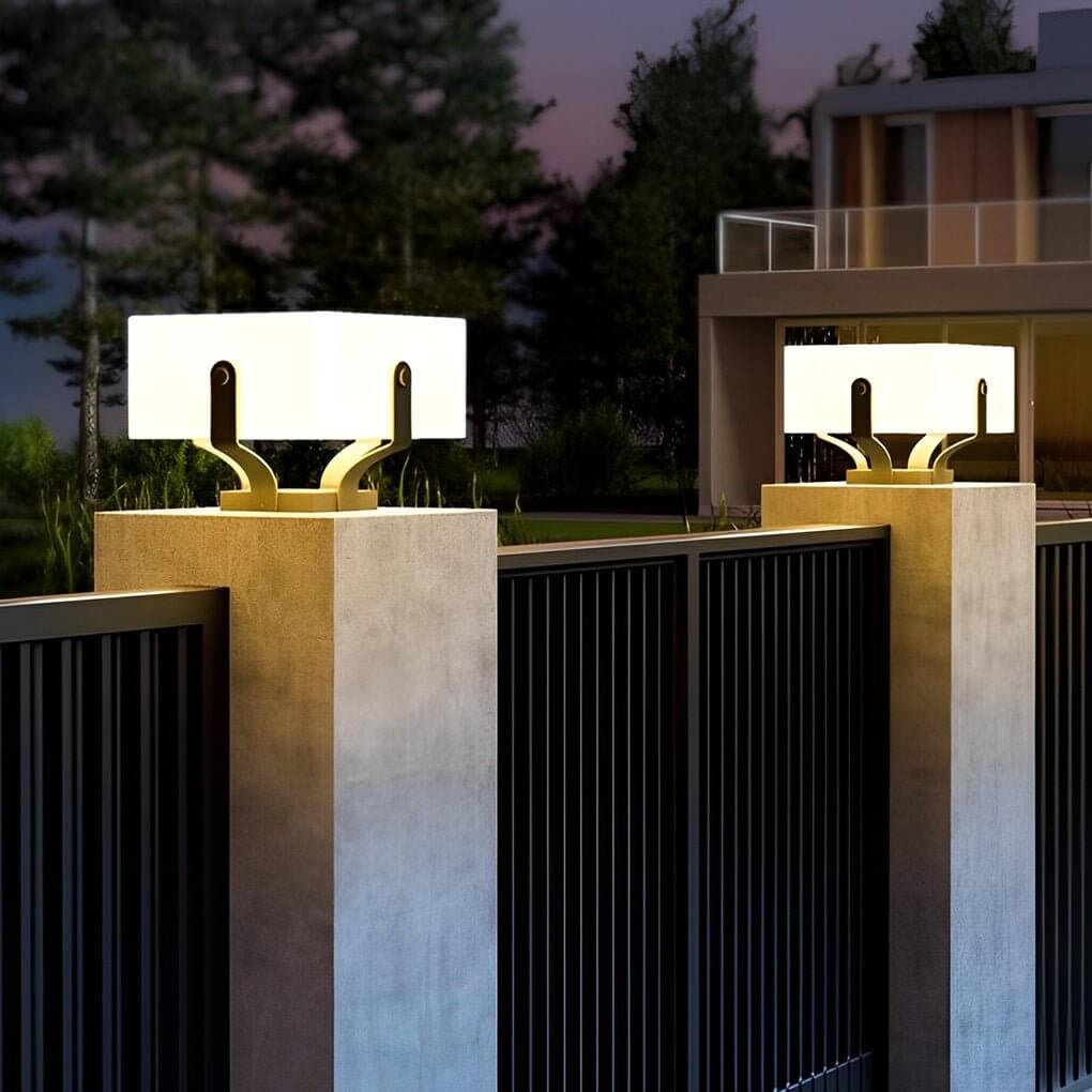 Outdoor brick pillar lights on a stone base, casting a soft light on the surrounding plants.