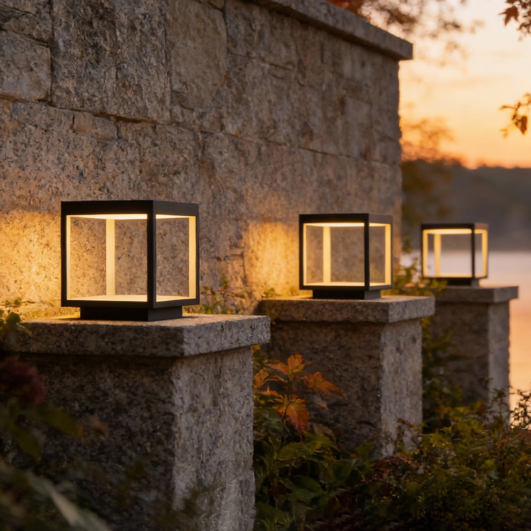 Outdoor concrete pillar lights lining a stone driveway wall