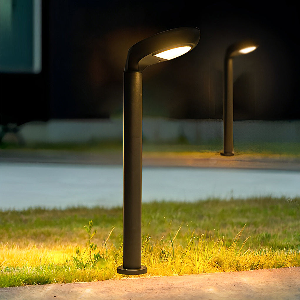 Outdoor curved bollard light casting warm light on grass and pavement.