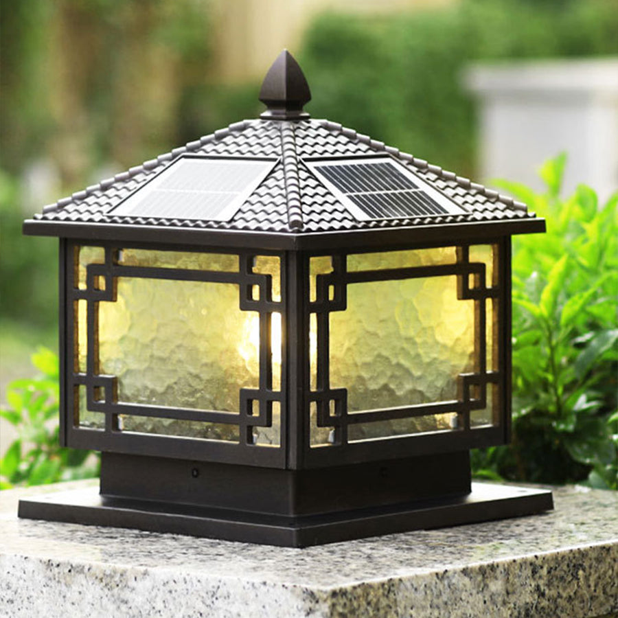 Outdoor garden pillar lights with a pagoda design, casting a soft glow in a lush garden setting.