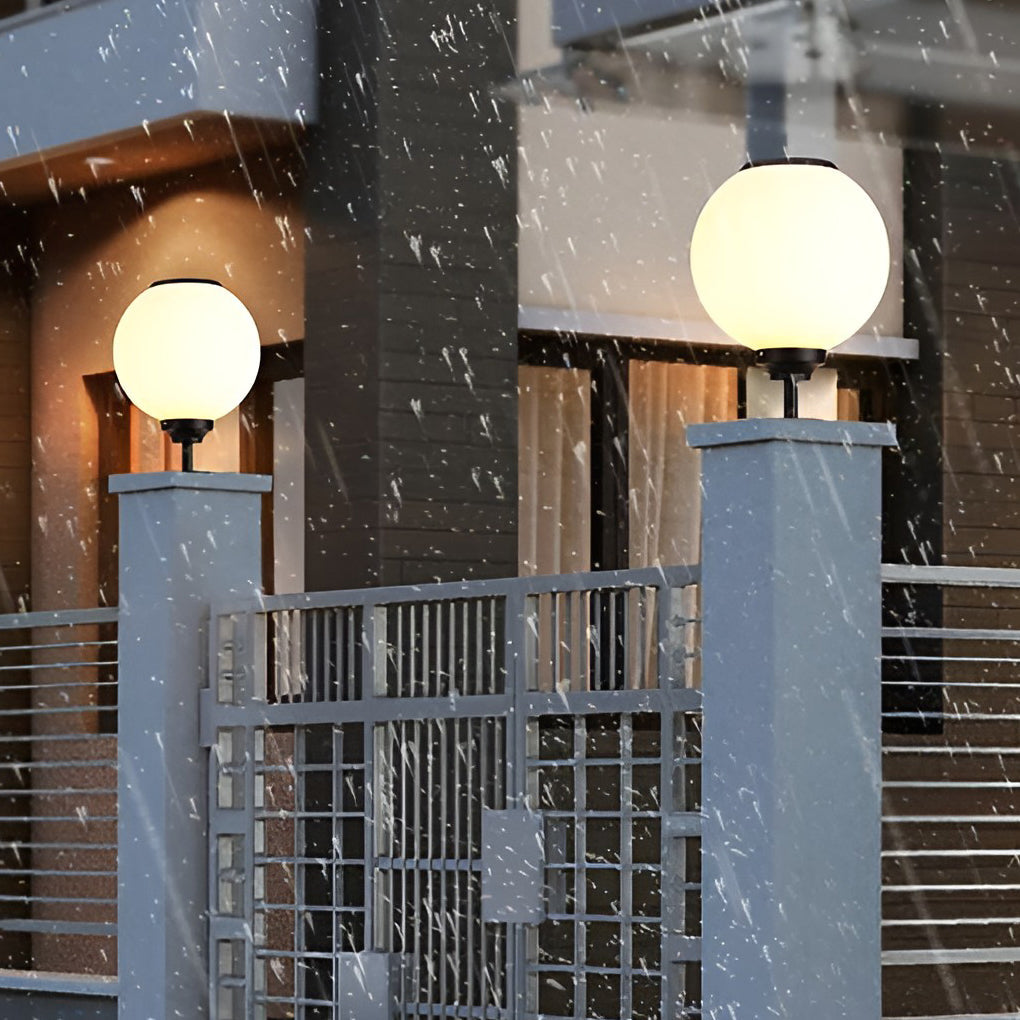 Outdoor gate pillar light with a spherical shape, providing bright illumination in a garden setting during twilight.