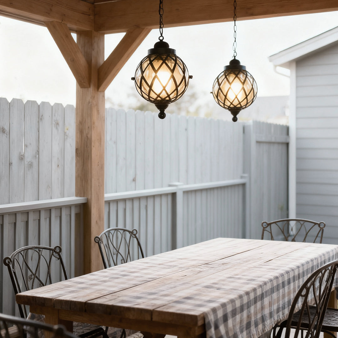 Pair of outdoor globe pendant lights hanging above a backyard dining table.