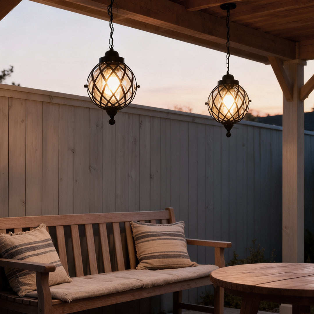 Two outdoor globe pendant lights hanging above a wooden bench under a covered patio.