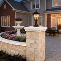 Outdoor landscape path lighting with a classic black design, mounted on a brick pillar near a garden.