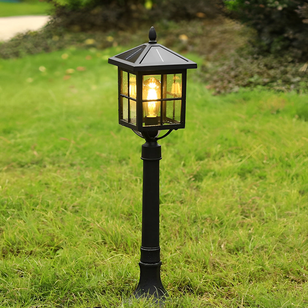 Outdoor lawn lights with a black finish, glowing softly in a garden setting.