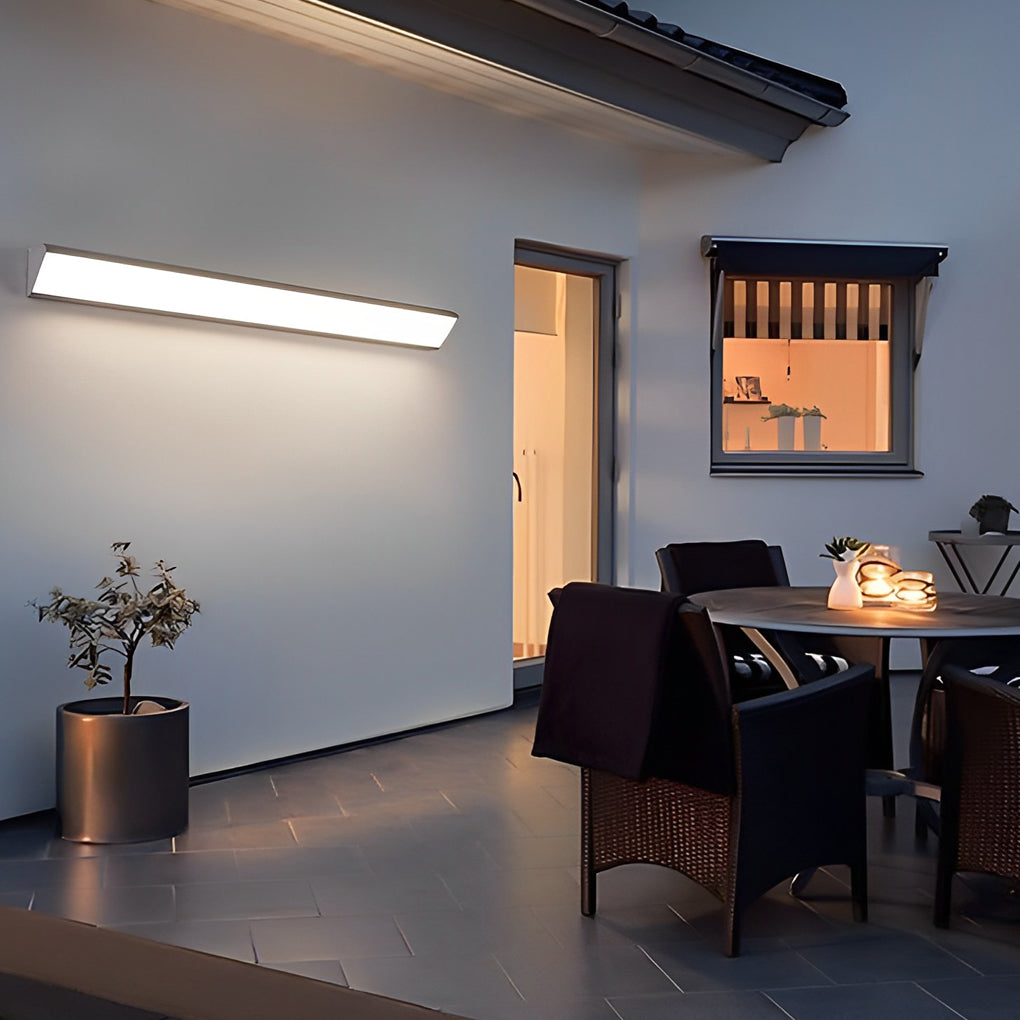 Outdoor LED wall sconce lighting a covered patio seating area at night.