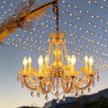 Outdoor lighting hanging with crystal details, illuminating a garden archway at dusk.