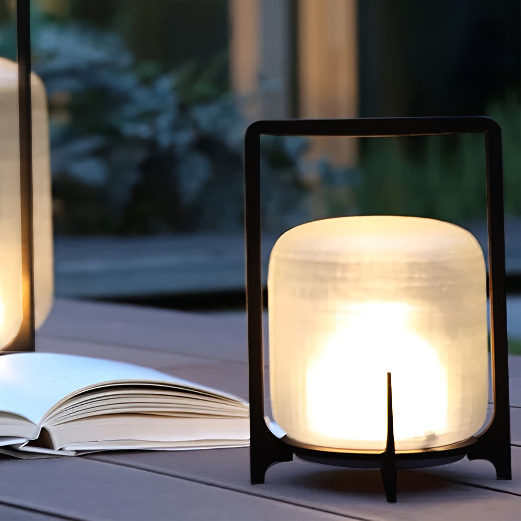 Outdoor modern handle lantern with frosted glass shade on wooden deck with green lawn.