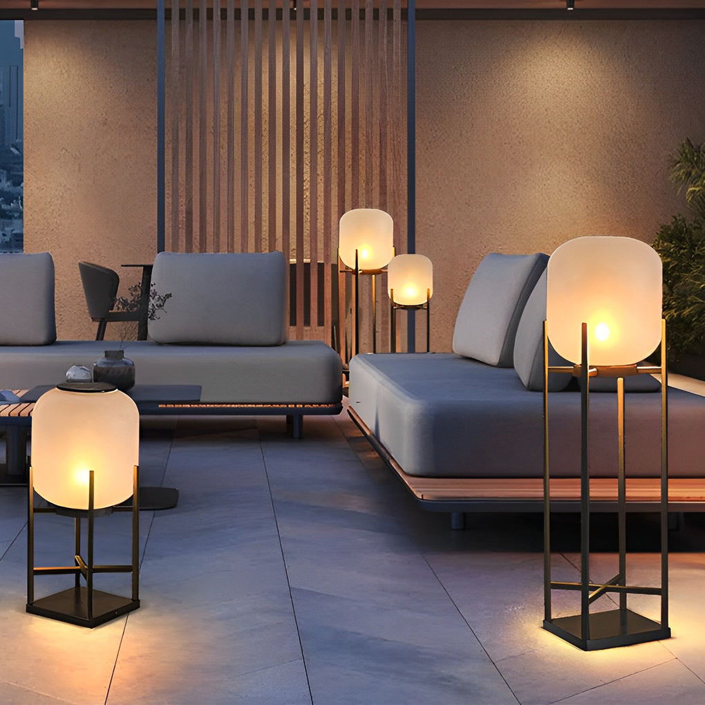 Outdoor standing light illuminating cozy seating area with cushions and fire pit on patio.