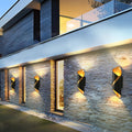 Outdoor up down wall light illuminating stone wall facade of contemporary building.
