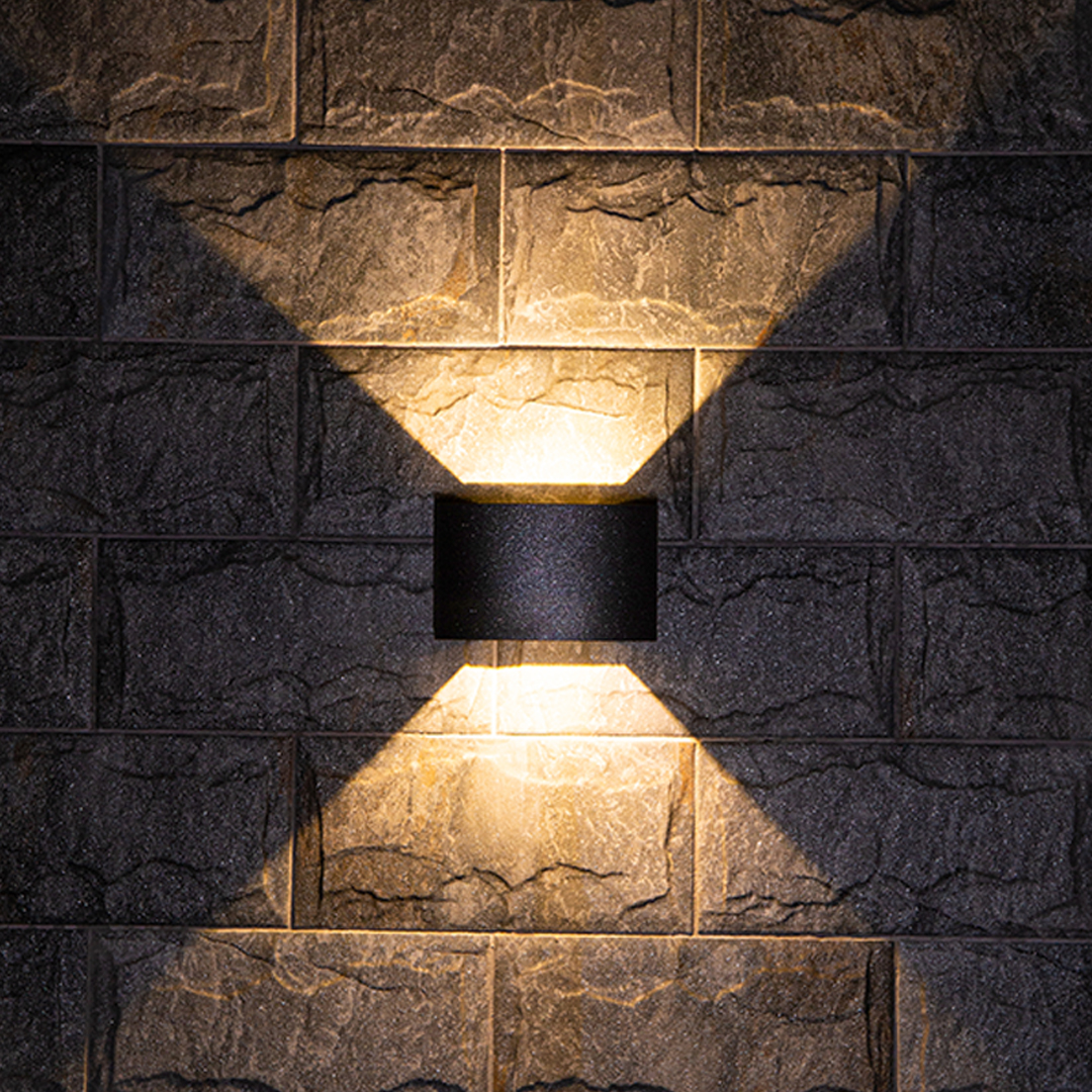 Outdoor up down wall light casting warm light on a stone wall exterior.