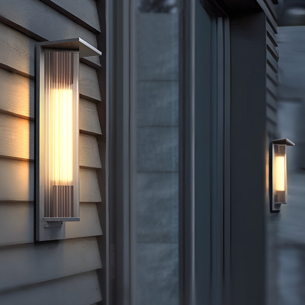 Outdoor vertical wall sconce illuminating a minimalist outdoor corridor with focused glow.