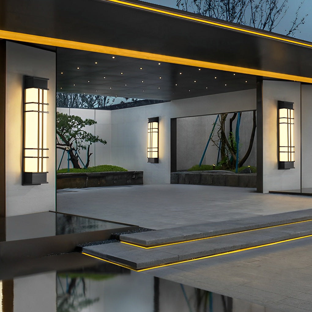 Outdoor wall sconce black with modern design, casting warm light on a white wall.