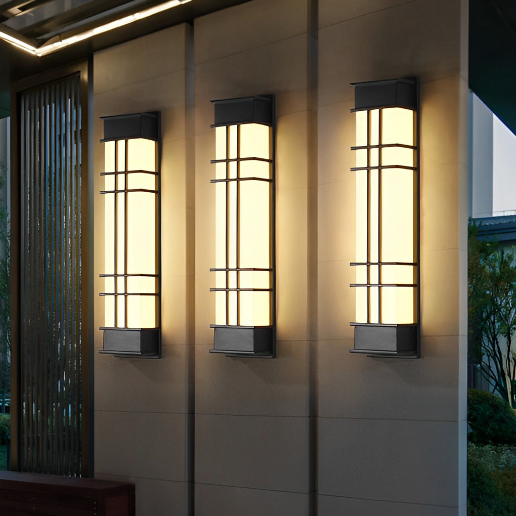Outdoor wall sconce black with vertical design, casting soft light on a stone wall.