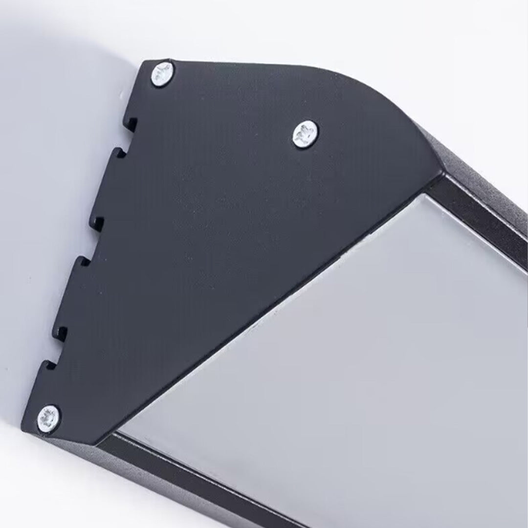 Close-up of black metal housing and mounting plate of an outdoor wall sconce.