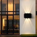 Outdoor wall sconce up and down lighting illuminating a modern building entrance with glass windows.