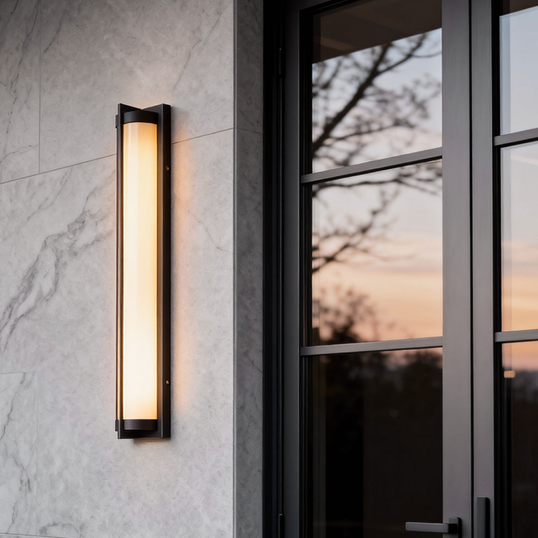 Outdoor wall sconces black mounted beside a modern entry door, featuring a slim rectangular frame with warm vertical light glow.
