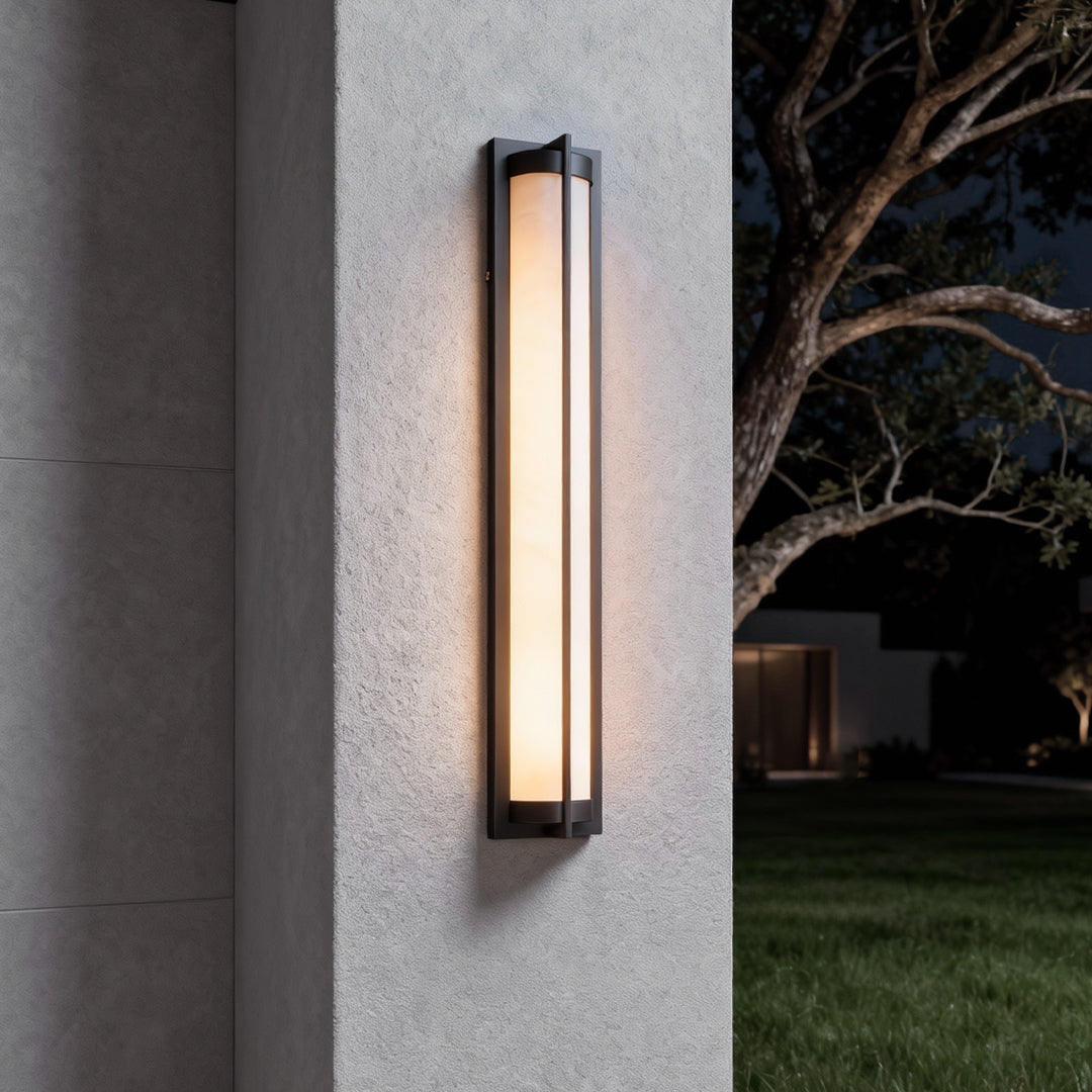 Outdoor wall sconces black installed on an exterior wall at dusk, showing a tall linear design with soft ambient illumination.