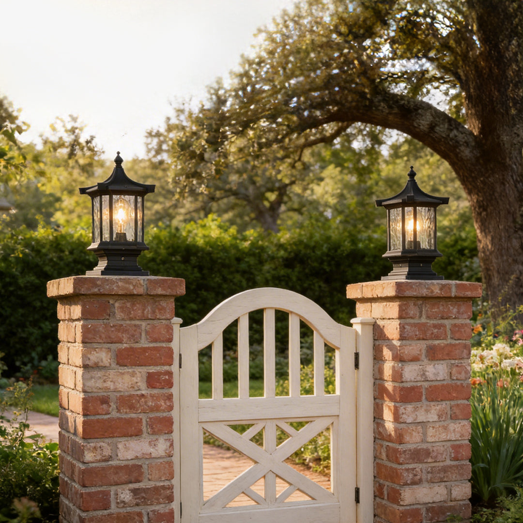 Pair of black lantern pillar lights flanking a white wooden garden gate on brick column bases.